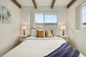 a white bedroom with a large bed and a window at NEW! Ocean View Mid-Century Modern Beach House in Manhattan Beach