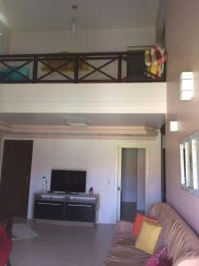 ein Wohnzimmer mit einem Sofa und einem Flachbild-TV in der Unterkunft SOBRADO COM PISCINA in Arroio do Sal