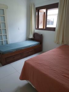 sypialnia z 2 łóżkami i oknem w obiekcie SOBRADO COM PISCINA w mieście Arroio do Sal