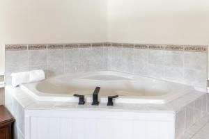 a white tub in a bathroom with a tile wall at Sara Placid Inn & Suites in Saranac Lake