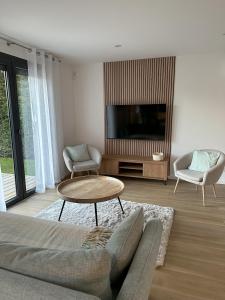 uma sala de estar com uma televisão, um sofá e uma mesa em Sunny House - Villa 4 chambres - Saint Genis Les Ollières em Saint-Genis-les-Ollières