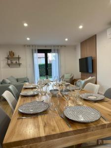 einen Holztisch mit Tellern und Weingläsern darauf in der Unterkunft Sunny House - Villa 4 chambres - Saint Genis Les Ollières in Saint-Genis-les-Ollières