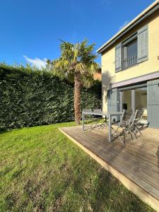 una terraza de madera con sillas, una mesa y una palmera en Sunny House - Villa 4 chambres - Saint Genis Les Ollières en Saint-Genis-les-Ollières