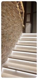 a set of white stairs with a stone wall at Elania Residence in Târgu Jiu