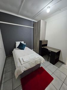 a bedroom with a bed with a desk and a red rug at Dunrobyn Court Tempo Stay 12 in East London