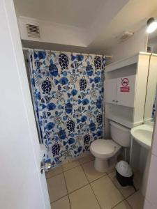 a bathroom with a toilet and a blue and white shower curtain at Departamento frente la costa de Coquimbo in Coquimbo