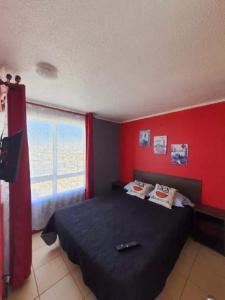 a bedroom with a black bed and red walls at Departamento frente la costa de Coquimbo in Coquimbo
