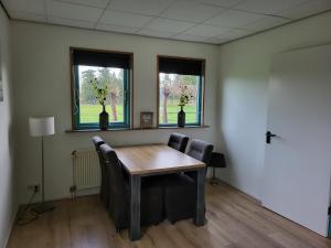 een kamer met een tafel en stoelen en 2 ramen bij Vakantiehuis Het Loar - Rust en Natuur in Vaassen