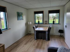 een kamer met een tafel, stoelen en ramen bij Vakantiehuis Het Loar - Rust en Natuur in Vaassen