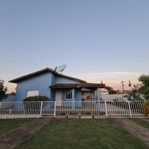 una casa azul con una valla blanca delante de ella en Casa em condomínio Ninho Verde 1 en Porangaba