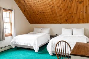 - 2 lits dans une chambre dotée d'un plafond en bois dans l'établissement Sara Placid Inn & Suites, à Saranac Lake