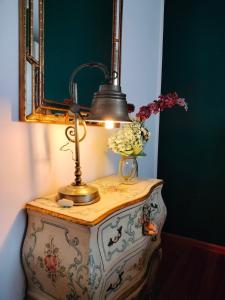 a lamp on a table with a vase of flowers on it at Maison Papà, una casa per sentirsi a casa. in Vicenza