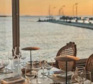 a table with glasses and chairs next to the water at Only2Suites in Athens