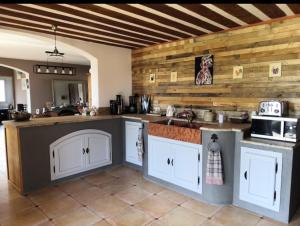 - une cuisine avec des placards blancs et un mur en bois dans l'établissement Belle Villa à la campagne avec piscine, à Brue-Auriac