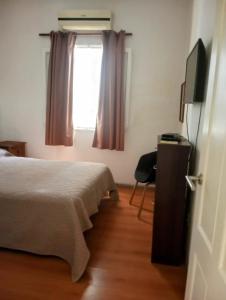 1 dormitorio con 1 cama, TV y ventana en Colibrí, en Piriápolis
