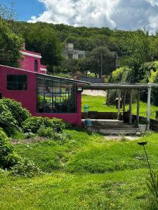 una casa rosa con ventanas de cristal en el césped en Rosadita loft en Río Ceballos