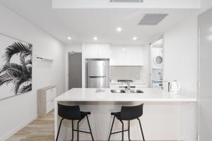 a kitchen with a white counter and two stools at 703Mer in Gold Coast