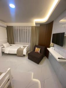ein Schlafzimmer mit einem Bett, einem Stuhl und einem TV in der Unterkunft Villa Jelena in Negotino