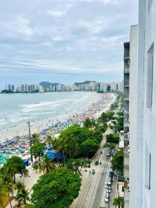 a beach with a lot of people and the ocean at Apartamento frente mar Guarujá Pitangueiras pé na areia in Guarujá