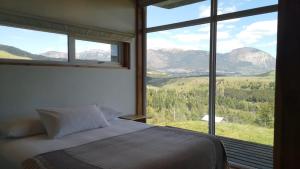 een slaapkamer met een bed en een groot raam met uitzicht op de bergen bij Cabañas Patagonia Indómita in Coihaique