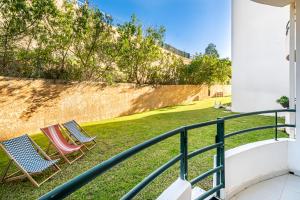 2 chaises assises sur l'herbe sur un balcon dans l'établissement BeGuest Falesia Beach & Garden, à Albufeira