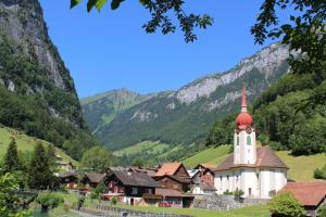 ein kleines Dorf mit einer Kirche in den Bergen in der Unterkunft Hotel Urirotstock in Isenthal