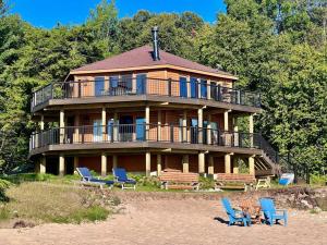 une grande maison sur la plage avec des chaises bleues dans l'établissement Lake Michigan Cabin w/Hot Tub & Stunning Views, à Manistique