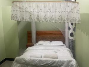 a bed with a canopy with two towels on it at The First Royal Tour Lodge in Dodoma
