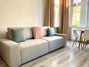 a living room with a couch with pillows on it at Agapella Apartamenty - Apartament Goyki 300 m from the beach in Sopot