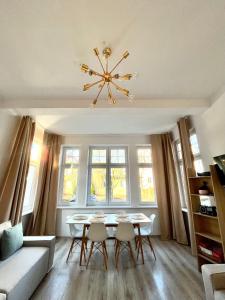 un soggiorno con tavolo, sedie e lampadario pendente di Agapella Apartamenty - Apartament Goyki 300 m from the beach a Sopot