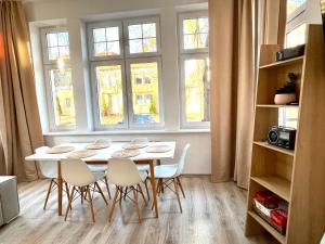 un tavolo con sedie in una stanza con finestre di Agapella Apartamenty - Apartament Goyki 300 m from the beach a Sopot