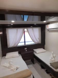 マナウスにあるAmazon Extreme River Fishのボート上の窓が備わる客室のベッド2台