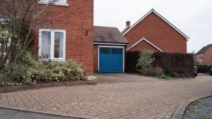 a red brick house with a blue garage at Luxurious Contractor/Family 6 Bedroom House in Shenley Church End