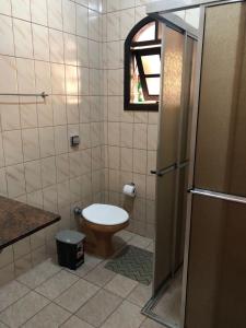 a small bathroom with a toilet and a window at Casa grande com churrasqueira - Centro Ubatuba in Ubatuba