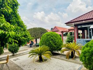 un jardin avec des palmiers et un bâtiment rose dans l'établissement Silent night, à Kumasi