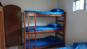 2 literas en una habitación con almohadas azules en Casa grande com churrasqueira - Centro Ubatuba en Ubatuba