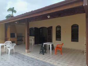 Casa grande com churrasqueira - Centro Ubatuba في أوباتوبا: مجموعة من الكراسي والطاولات على الفناء