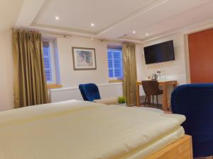 Un dormitorio con una cama y sillas y un televisor. en Hotel Zur Stadt Cassel, en Neukirchen