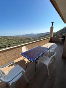 a table and chairs on a balcony with a view at Villa Arriba in Periana