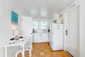 eine Küche mit einem weißen Kühlschrank und einem Tisch in der Unterkunft Sandcastle Cottage 22 - Historic oceanfront studio with direct beach access in Oceanside