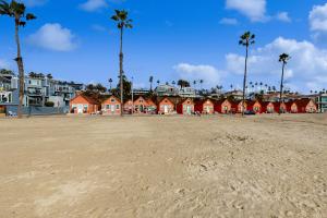 einen Sandstrand mit roten Häusern und Palmen in der Unterkunft Sandcastle Cottage 22 - Historic oceanfront studio with direct beach access in Oceanside