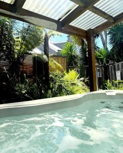 an outdoor swimming pool with a pergola and a swimming pool at Southpacific Motel in Whangamata