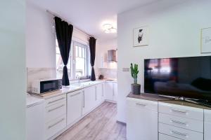 cocina con armarios blancos y TV de pantalla plana en LAGUNA Apartament Willa Ogrodowa 17, en Polanica-Zdrój