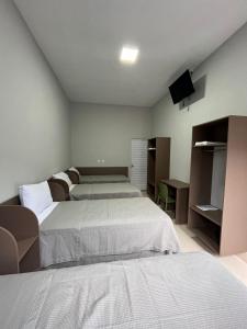 een slaapkamer met 2 bedden en een tv aan de muur bij Hotel Xangrilá in Salinas