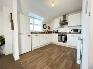 a kitchen with white cabinets and a wooden floor at Modern Flat near Birmingham Uni with Wi-Fi & Parking in Birmingham