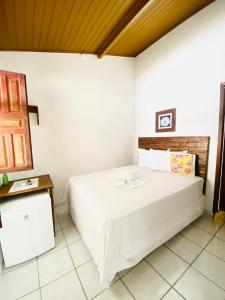 a bedroom with a white bed and a wooden ceiling at Pousada Arraial da Poesia in Arraial d'Ajuda