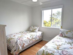 um quarto com uma cama e uma janela em Whale Tail Beach House em Pambula Beach