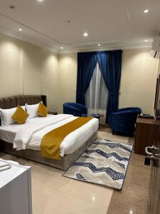 a bedroom with a large bed and blue chairs at فلور الخليجية للشقق المخدومة Flowersuite1 in Dammam