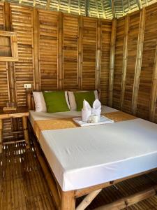 een bed in een bamboekamer met een dienblad met handdoeken bij Mecaja Beach House in Roxas