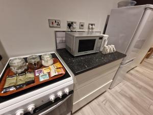 a kitchen with a microwave on top of a counter at Self contained studio flat in Luton -Close to luton airport - Luton Dunstable Hospital - Business contractors - Family - All welcome -Short or Long Stay in Luton